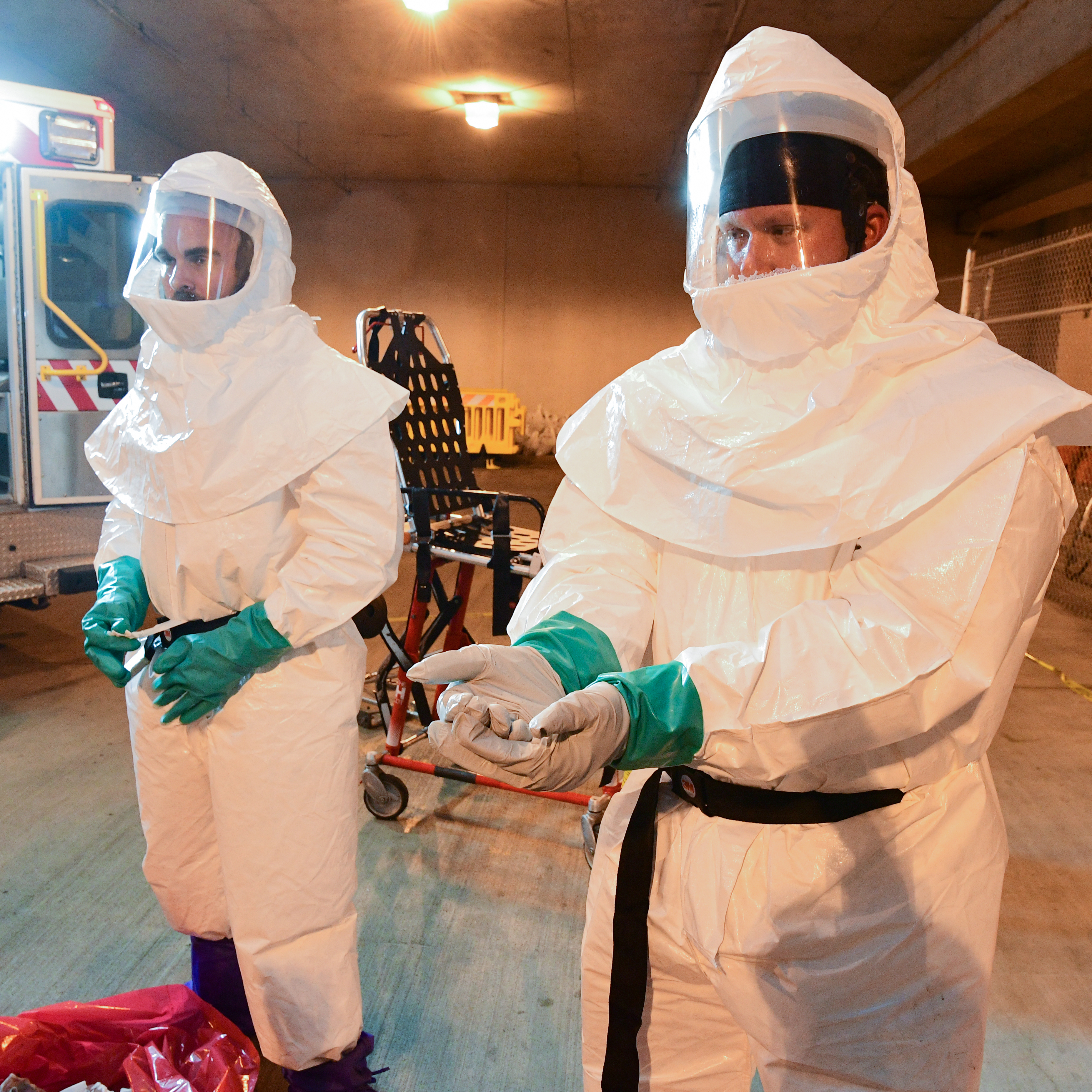 Two people suiting up into the protection suit and putting on gloves